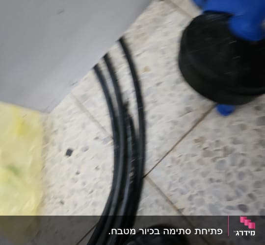 צינורות שחורים על רצפה ליד כלי עבודה כחול